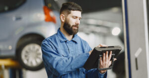 homem mecânico que trabalha com reparação automotiva com tablet na mão
