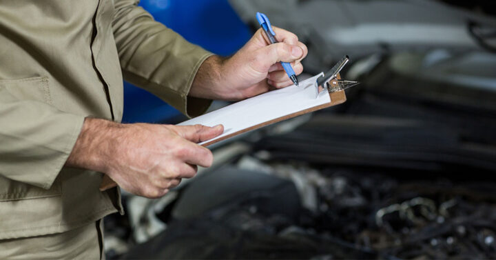 homem com prancheta na mão e escrevendo numa planilha de manutenção preventiva de veículos como fazer